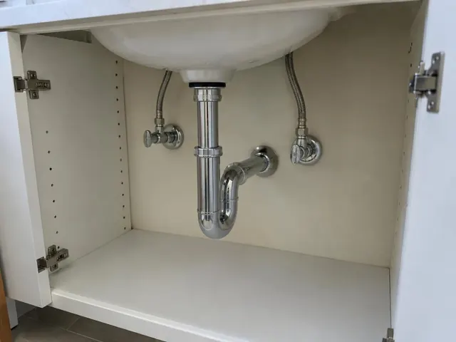 Neat under-sink cabinet with chrome trap, flex hoses and dry access panel in Killara